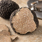 Cut Summer Black Truffle Tuber aestivum showing light marbled interior and rough black skin